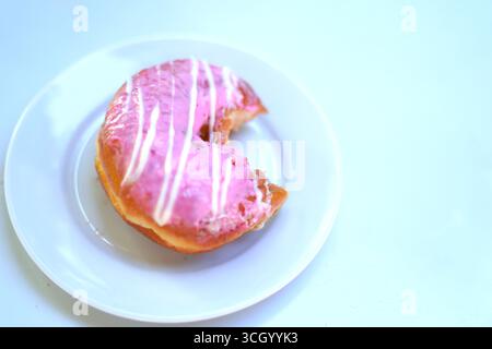 Freshly Baked Bite pink Donut Served on White Plate. Stock Photo