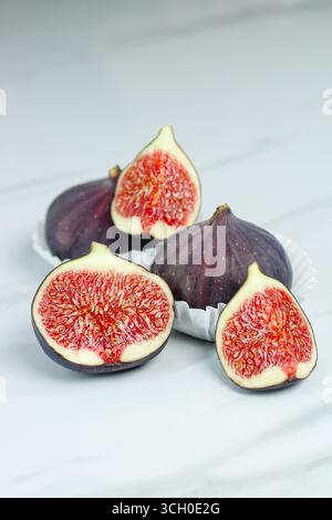 Cut purple figs on marble kitchen counter. Ripe and sweet summer fruit. Stock Photo