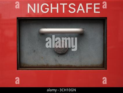 Close-Up Of A Bank Nightsafe Deposit Box With A Metal Handle And Lock On A Red Background Stock Photo