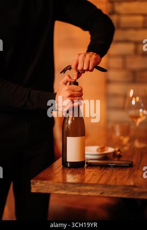 Sommelier uncorking wine bottle in elegant restaurant, preparing for refined wine service Stock Photo