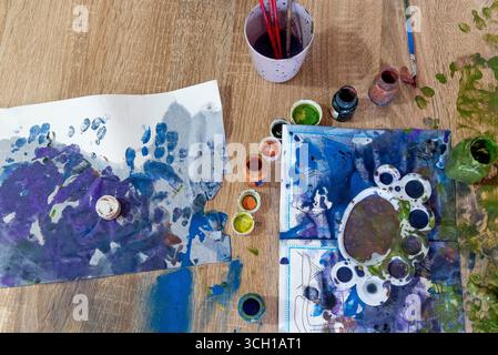 Top view of the mess on the table, the child smeared art the surface with colored gouache paint Stock Photo