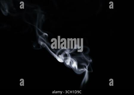 A graceful swirl of smooth white smoke against a dark background, forming a beautiful flowing shape Stock Photo
