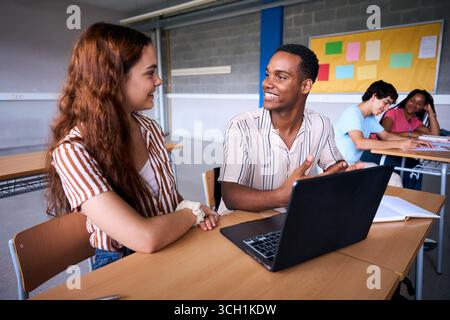 High school students collaborating on project with laptop in classroom Stock Photo