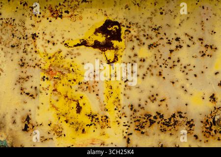 Rusty yellow metal surface with extensive corrosion and peeling paint on an old industrial door, close-up abstract texture, urban setting. Stock Photo