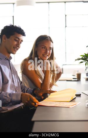 Diverse colleagues reviewing documents at office, discussing project details with interest Stock Photo