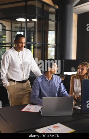 Collaborating on project, business diverse professionals with laptop and documents in office Stock Photo