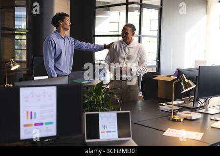 Diverse colleagues discussing project in modern office, smiling and collaborating on ideas Stock Photo