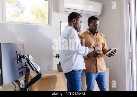 Two men discussing project details while using tablet in modern office Stock Photo