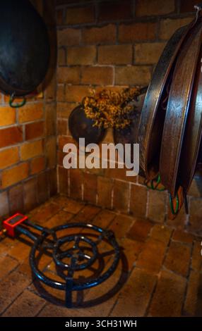 Rustic kitchen with hanging paella pans of different sizes and a gas paella burner to cook authentic and traditional Valencian paella. Stock Photo