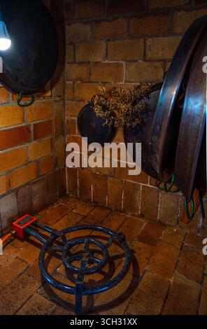 Rustic kitchen with hanging paella pans of different sizes and a gas paella burner to cook authentic and traditional Valencian paella. Stock Photo