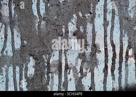 Dirty black spray paint with drips on a blue wall texture Stock Photo