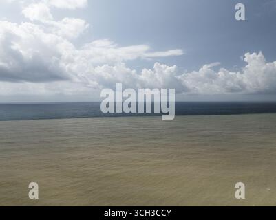 Aerial view of the stark contrast between the muddy river outflow and the dark sea under a cloudy sky, Kobuleti, Adjara, Georgia. Stock Photo
