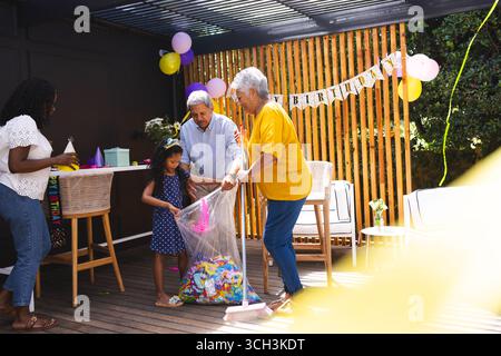 At party, Happy family cleaning up after birthday party on patio, enjoying time together Stock Photo