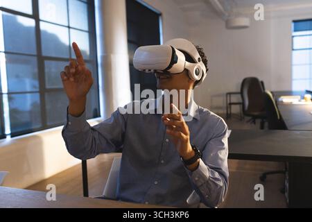 In office, man using VR headset and interacting with virtual environment Stock Photo
