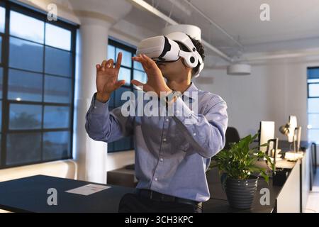 Businessman using VR headset in modern office, exploring virtual environment Stock Photo