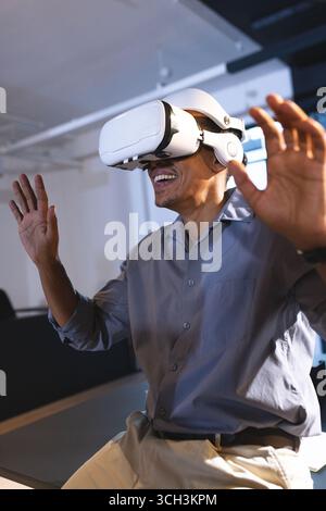 In office, man using VR headset, smiling and interacting with virtual reality Stock Photo