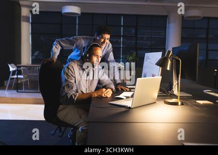 Business diverse professionals collaborating on laptop and analyzing data in modern office Stock Photo