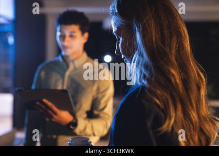 Business diverse professionals discussing project using tablet at night in office Stock Photo