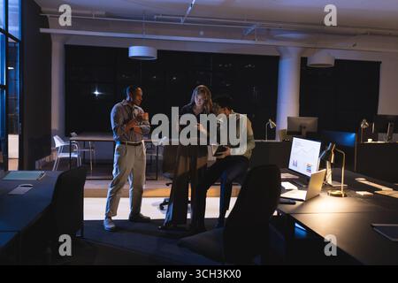 Business diverse professionals collaborating on tablet in modern office during late night Stock Photo