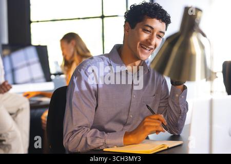 Smiling man in office writing notes at desk during business meeting Stock Photo