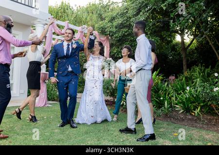 Joyful wedding celebration with bride and groom dancing surrounded by happy friends Stock Photo