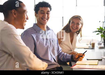 Colleagues in office discussing project, smiling and collaborating with documents Stock Photo