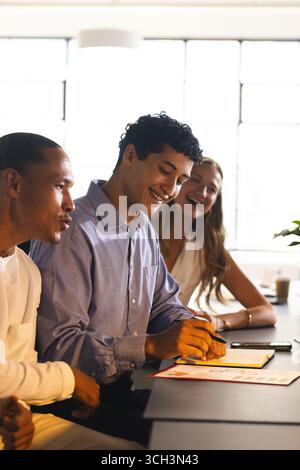 Colleagues collaborating at office, smiling and discussing ideas during meeting Stock Photo