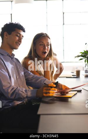 Colleagues discussing project at office desk, sharing ideas and smiling Stock Photo