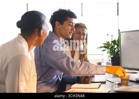 Business team collaborating on project, analyzing data on computer in modern office Stock Photo