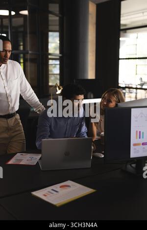 Collaborating on project, business professionals using laptop and charts in office Stock Photo