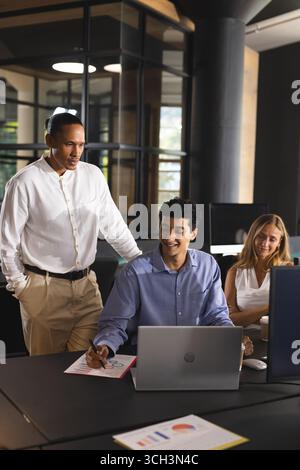 Collaborating in modern office, business professionals discussing project details on laptop Stock Photo