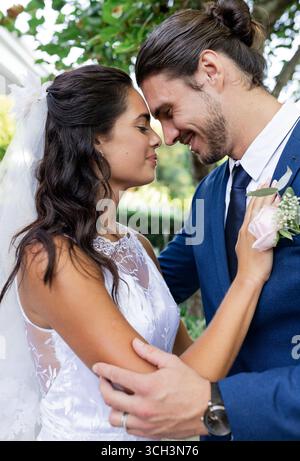 Bride and groom embracing outdoors, smiling and sharing joyful moment Stock Photo