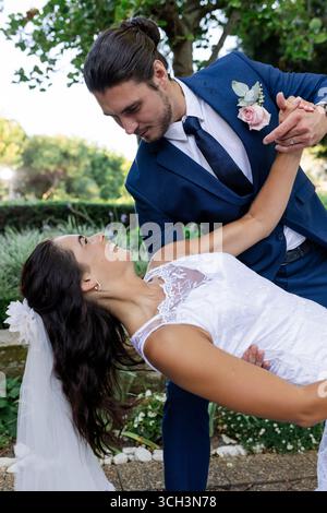 Bride and groom dancing joyfully outdoors, sharing romantic moment together Stock Photo