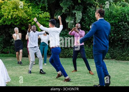 Celebrating joyfully, guests dancing energetically at outdoor wedding reception Stock Photo