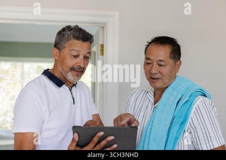 Two senior men using tablet at home, discussing and enjoying technology together Stock Photo