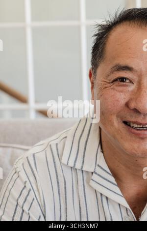 Smiling Asian senior man relaxing at home, enjoying peaceful moment Stock Photo