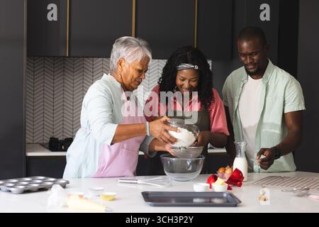 Three happy generations baking in kitchen, sharing joy and happy family traditions, at home Stock Photo