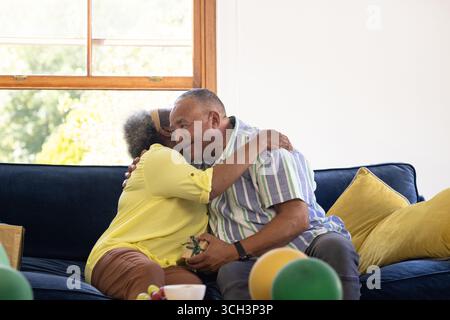 Senior couple embracing on sofa, sharing joyful moment at home Stock Photo