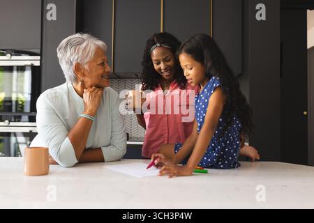 Three happy generations of women enjoying time at kitchen table with coffee, at home Stock Photo