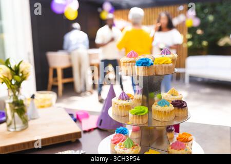 At party, Cupcakes on display at happy family gathering, people celebrating in background Stock Photo