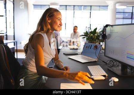 Analyzing data on computer, businesswoman in modern office, smiling confidently Stock Photo