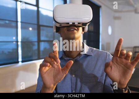 Man using VR headset in modern office, exploring virtual reality technology Stock Photo