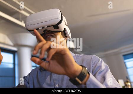 Using VR headset, man interacting with virtual environment in office enthusiastically Stock Photo