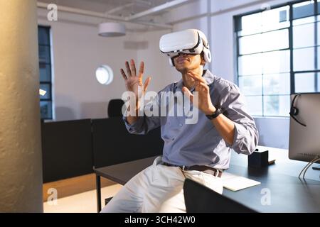 Businessman using VR headset at office, exploring virtual reality with excitement Stock Photo