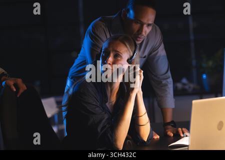 Business professionals collaborating at night, discussing strategy in modern office Stock Photo