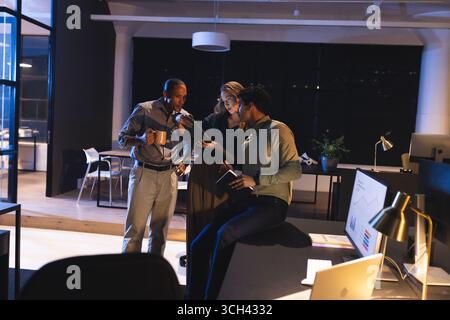 Business professionals discussing project details in modern office during late hours Stock Photo