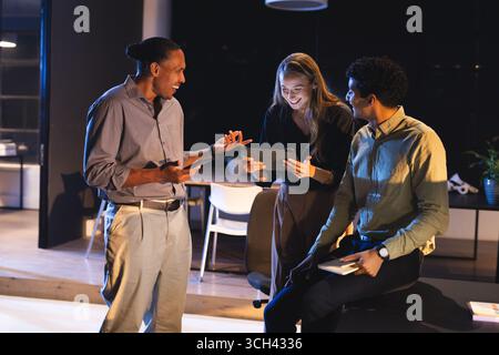 At night in modern office, business professionals collaborating using digital tablets Stock Photo