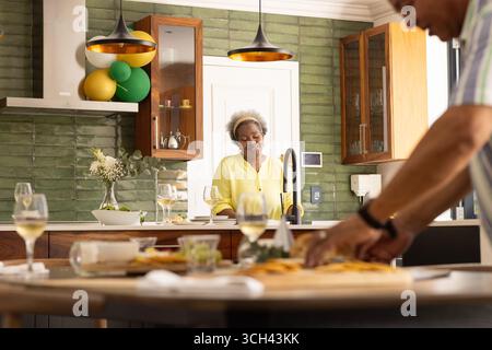 Senior couple enjoying wine and preparing meal together in modern kitchen Stock Photo