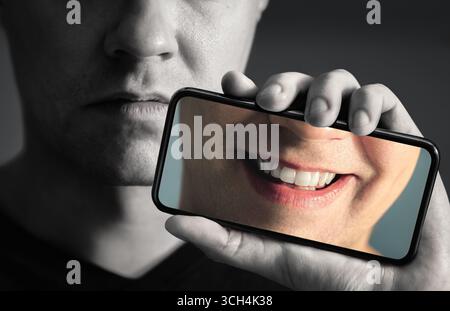 Bipolar, sad, happy face in phone. Mood change, mental disorder, or personality swing. Fake smile. Therapy recovery from depression. Stock Photo