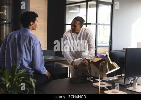 Colleagues discussing project details in modern office, engaging in teamwork Stock Photo